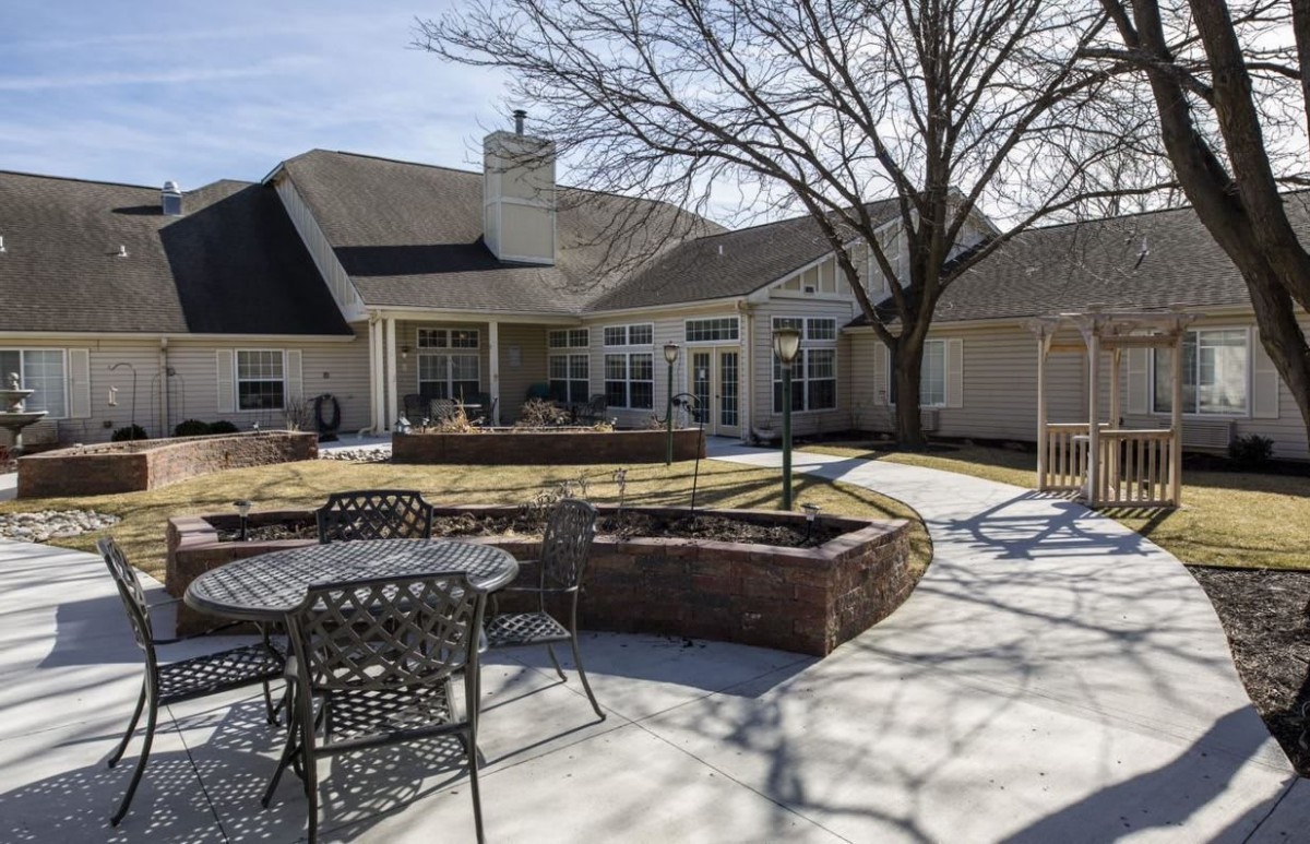 Sunny backyard patio with outdoor furniture and a tree.