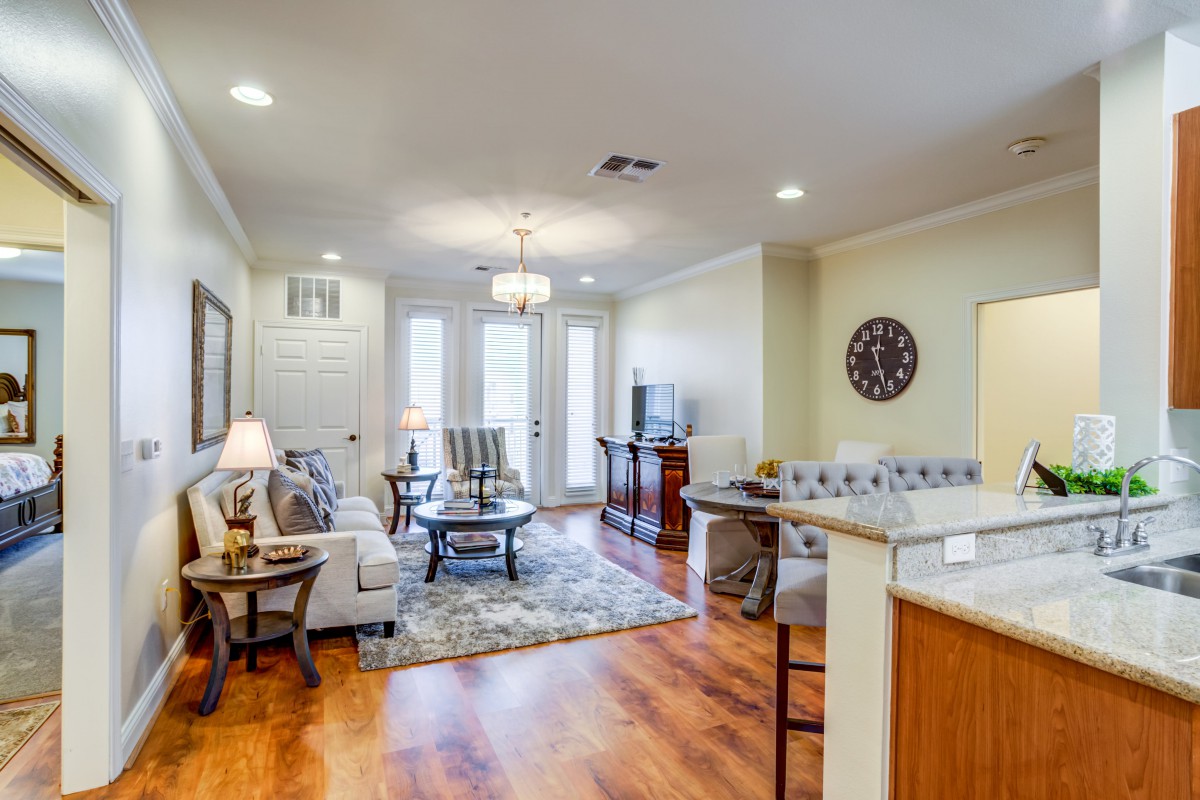 A cozy living room with stylish furniture and hardwood flooring, featuring a sofa, coffee table, and elegant lighting.