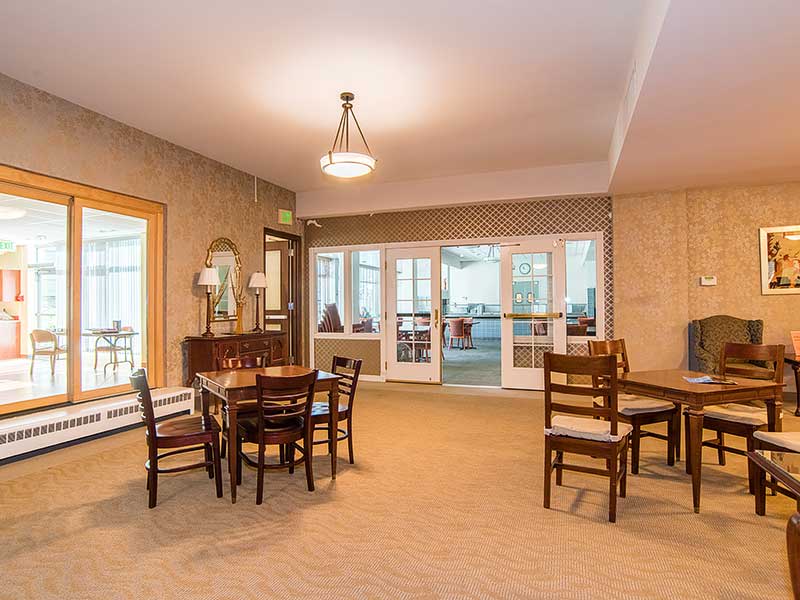 A well-lit interior dining area featuring tables and chairs, with a mirror and decor on the wall.
