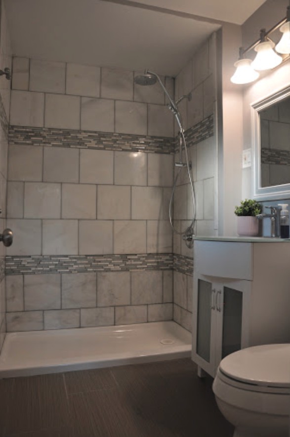 A modern bathroom with tiled walls and a shower area.