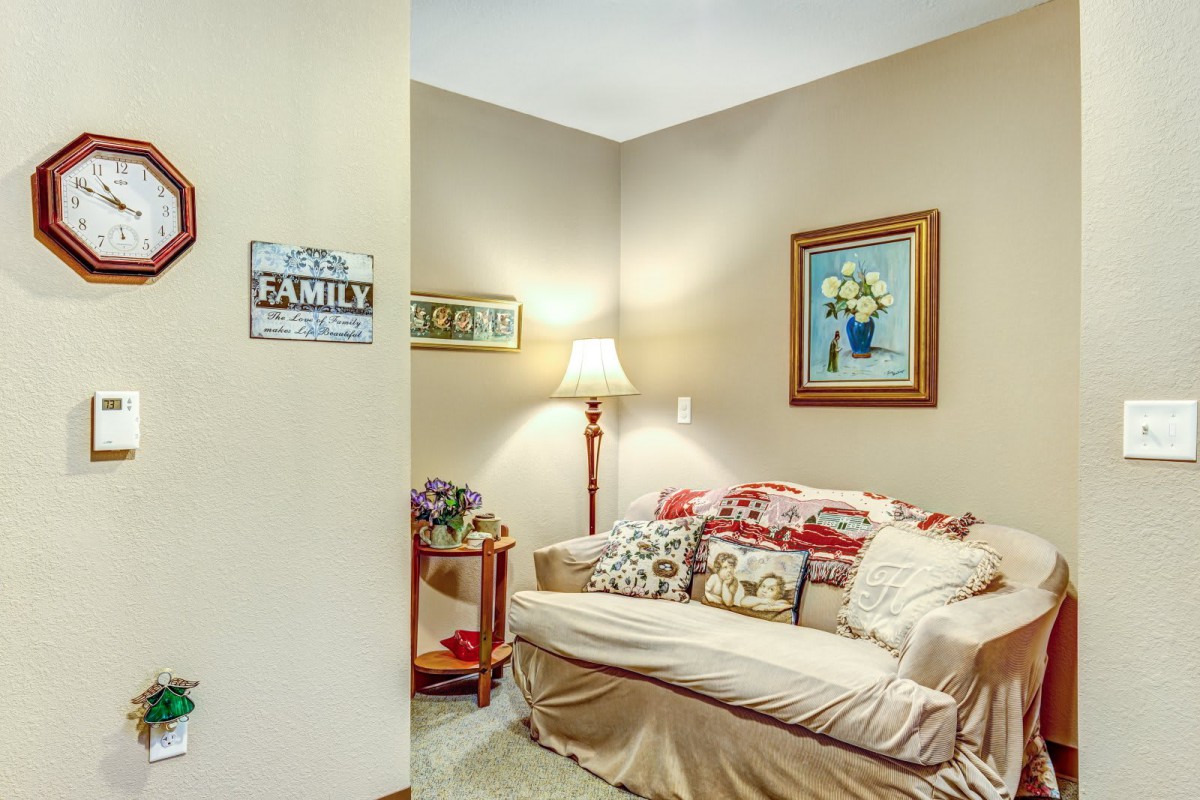 A cozy living room corner with a sofa, decorative pillows, and a floor lamp.