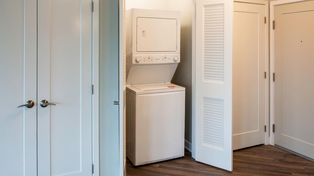 A stacked washer and dryer set inside a closet.
