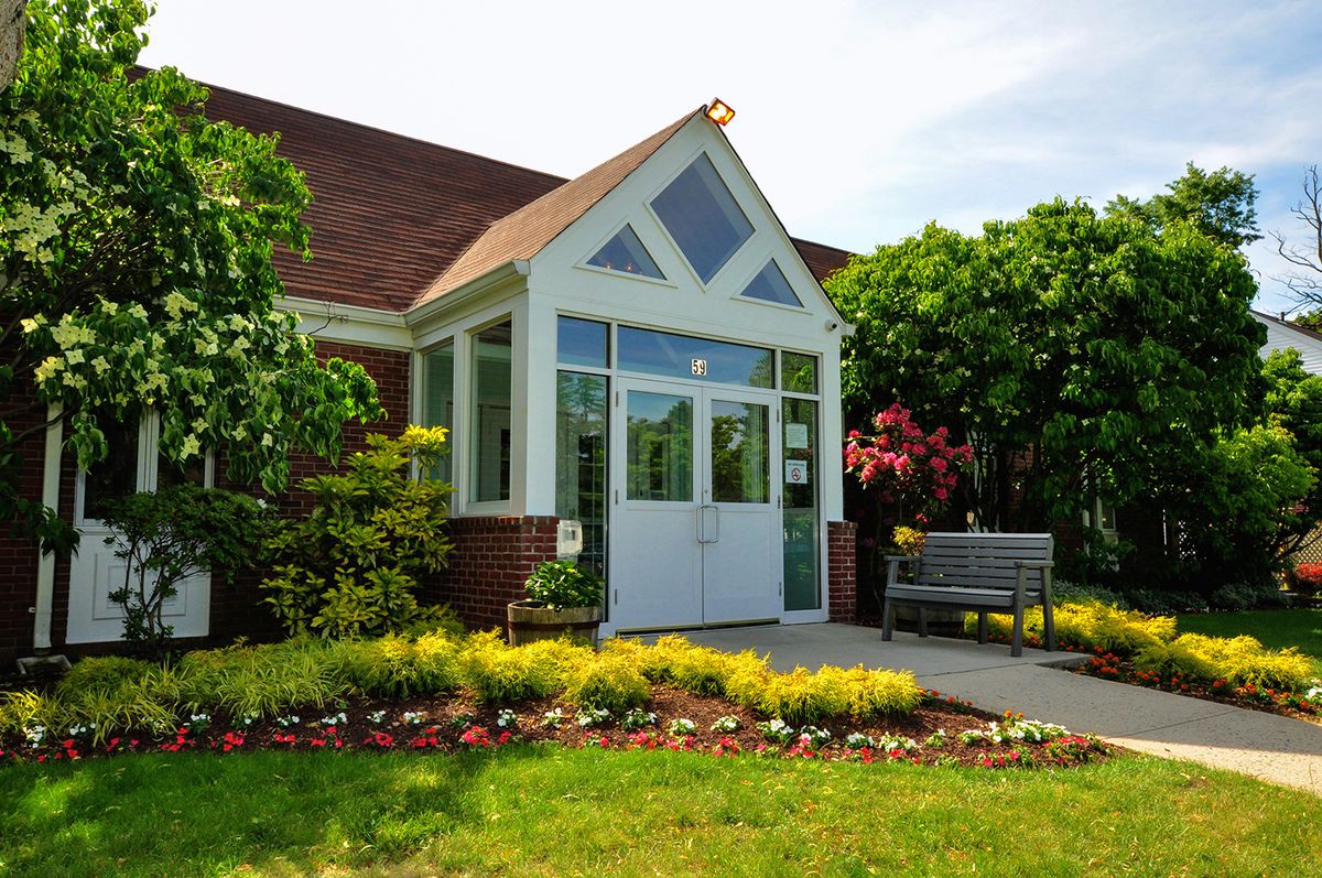 A charming building entrance surrounded by lush greenery and colorful flowers.
