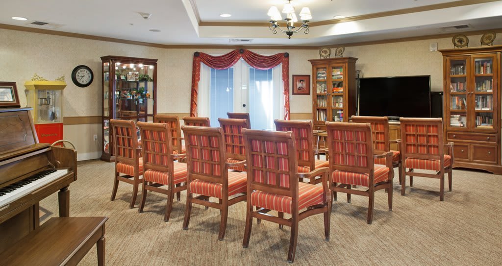 A neatly arranged meeting room with rows of chairs facing a bookshelf and television.