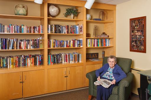 An elderly woman enjoying a book in a cozy library setting.