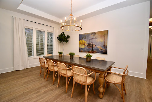 A stylish dining room featuring a large wooden table surrounded by elegant chairs and adorned with decorative plants.