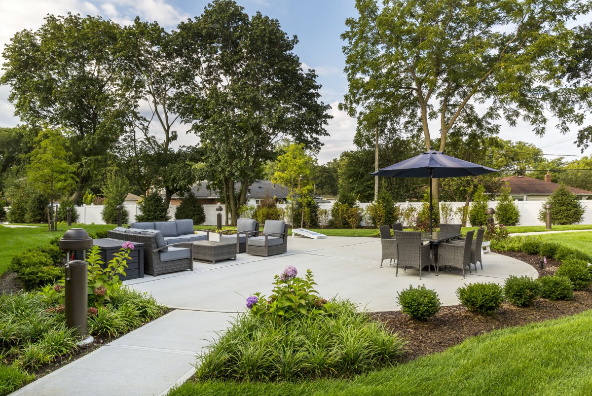 A beautifully landscaped backyard patio area with seating and umbrellas.