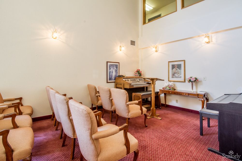 A small, elegantly decorated room with upholstered chairs and a lectern.