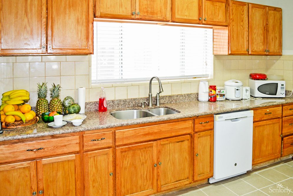 A clean and bright kitchen with wooden cabinets, a double sink, and various appliances on the countertop.