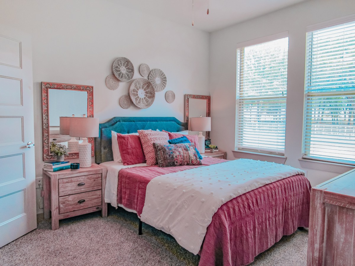 A cozy bedroom with stylish decor, featuring a bed, nightstands, lamps, and decorative wall art.