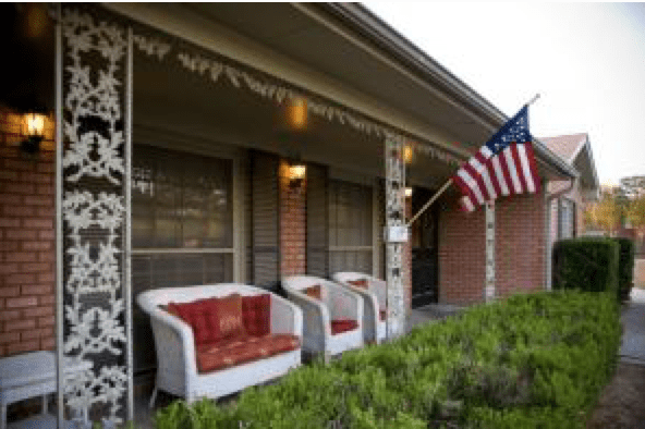 A cozy porch with chairs and an American flag in the evening light.