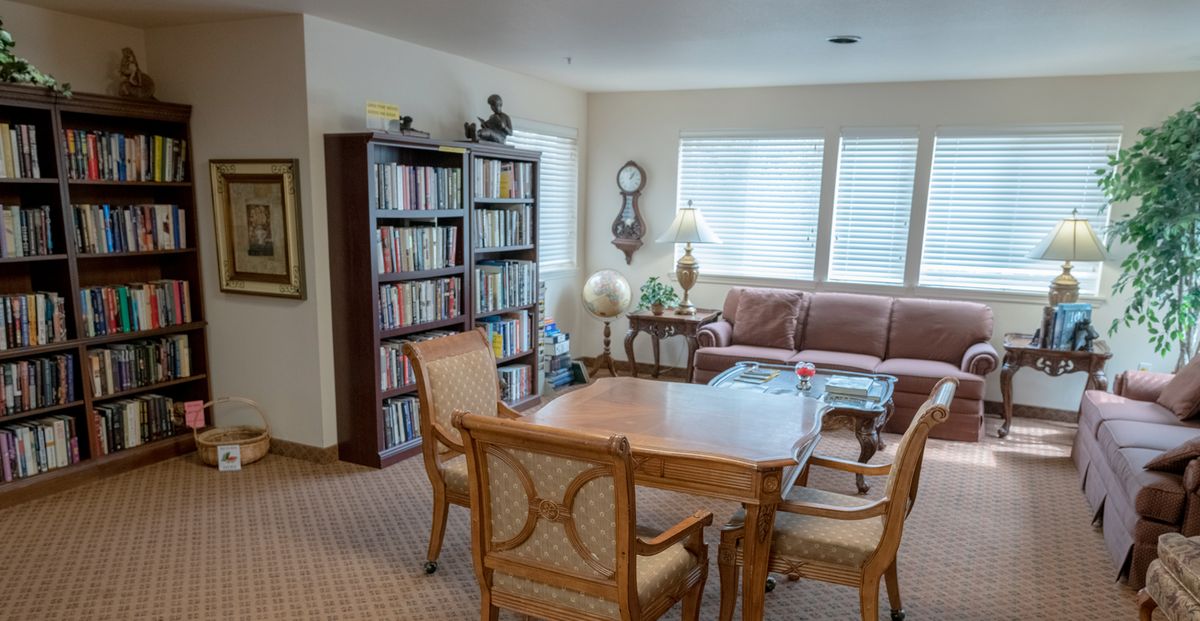 A cozy library corner with a table, chairs, and bookshelves filled with books.