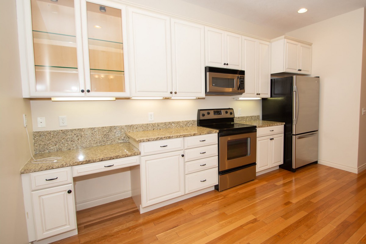 A modern kitchen with white cabinets, granite countertops, and stainless steel appliances.