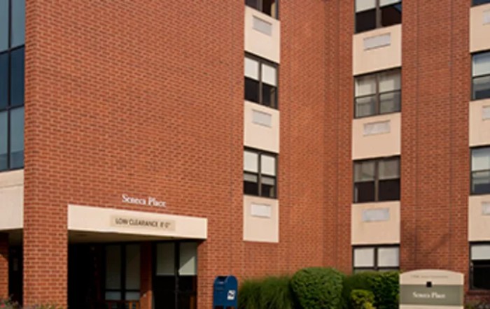 A brick building featuring multiple windows and a blue mailbox near the entrance.