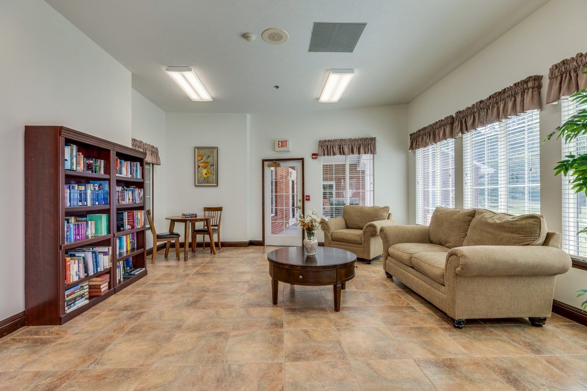 A cozy living room with bookshelves, a comfortable sofa set, and a central coffee table, offering a welcoming space for relaxation and reading.