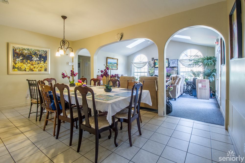 A cozy dining area with a large table and chairs, featuring arched doorways and ambient lighting.