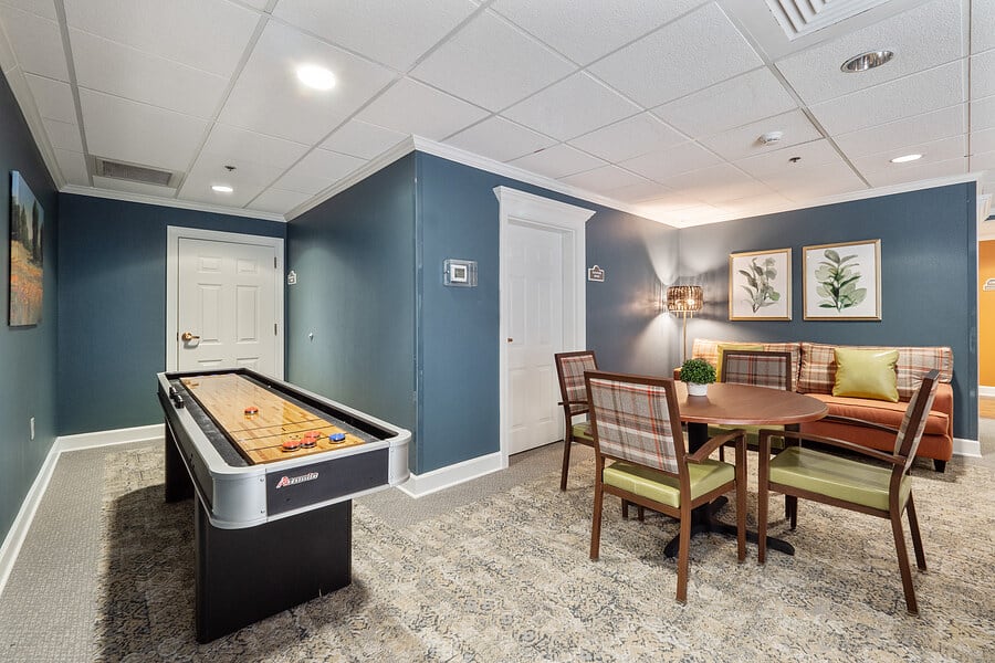 A modern game room featuring a shuffleboard table and a comfortable seating area.
