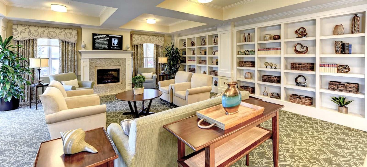 A cozy and elegantly designed living room featuring comfortable seating, a fireplace, and built-in shelves filled with decor.