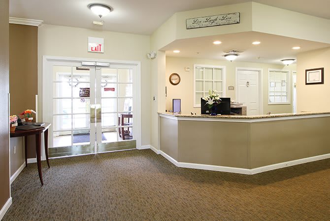 A welcoming reception area with a front desk and glass double doors.