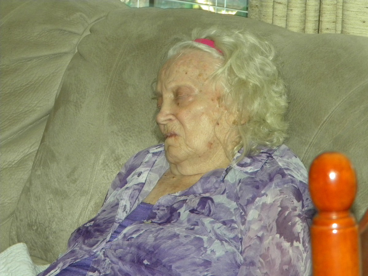 An elderly woman sleeping peacefully on a sofa indoors.