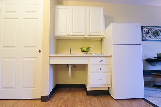 A simple kitchen setup with white cabinets, a countertop, and a fridge.