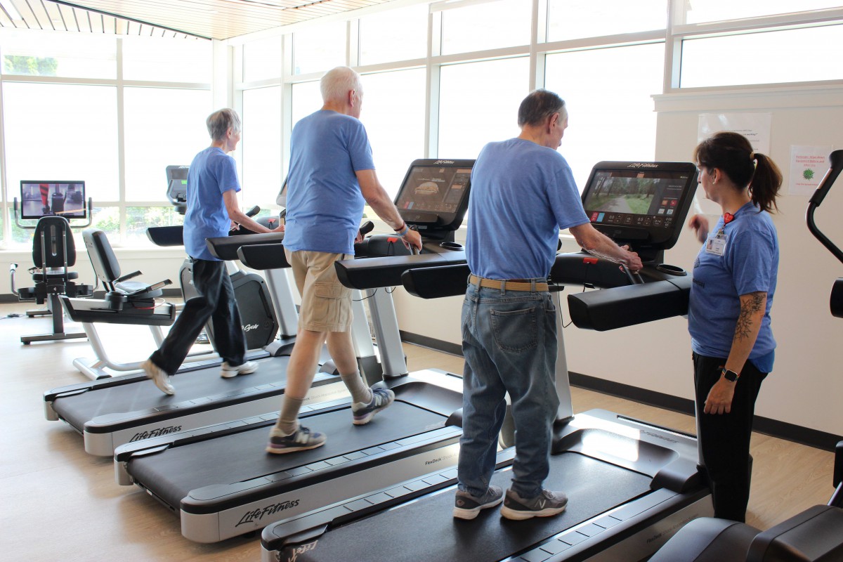 A group of people exercising on treadmills at a gym.