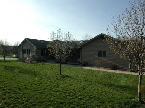 A suburban house with a spacious lawn and a few trees.