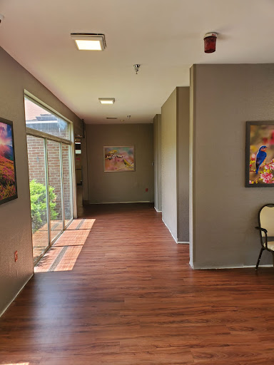 A bright and modern hallway featuring artwork on the walls and wooden flooring.