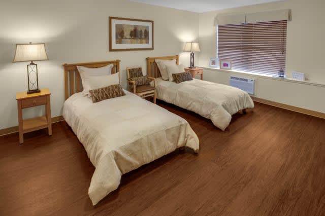 A cozy bedroom with twin beds and wooden flooring.