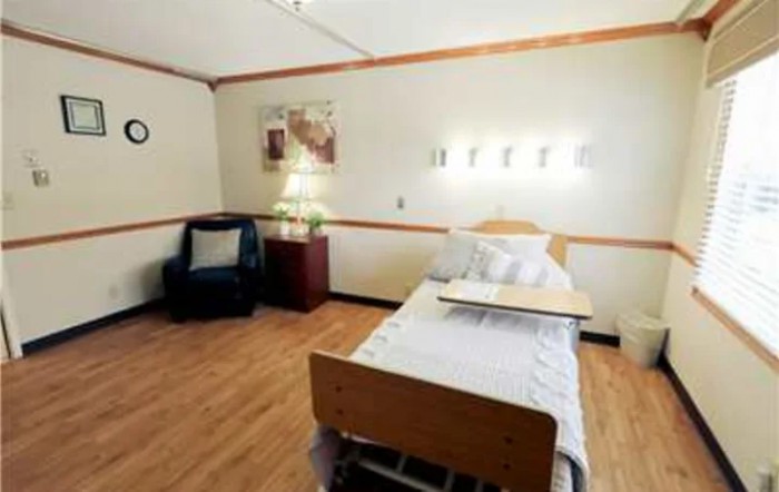 A clean and organized hospital room with a single bed and medical equipment.