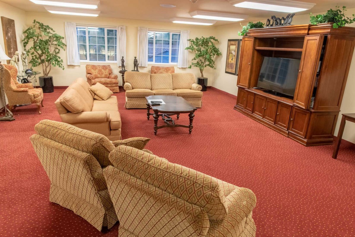 A cozy living room with plush sofas, a large TV, and warm lighting.