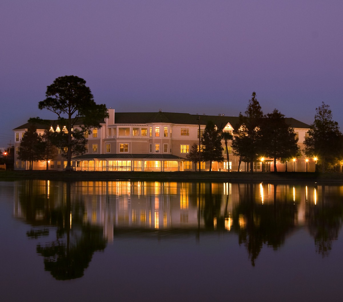A beautifully lit building reflecting on a calm lake at night.