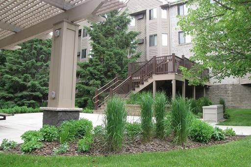 An apartment building with surrounding greenery and outdoor stairs.