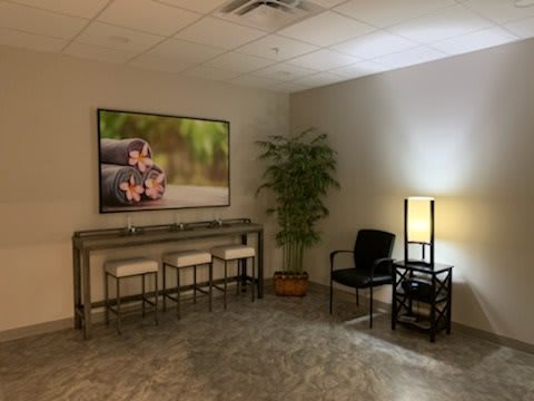 A cozy waiting room with seating, artwork, and a floor lamp.