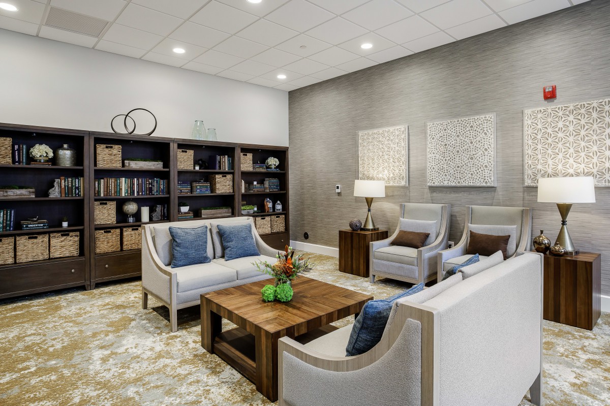 A modern living room featuring comfortable sofas, armchairs, a coffee table, and a stylish bookshelf.