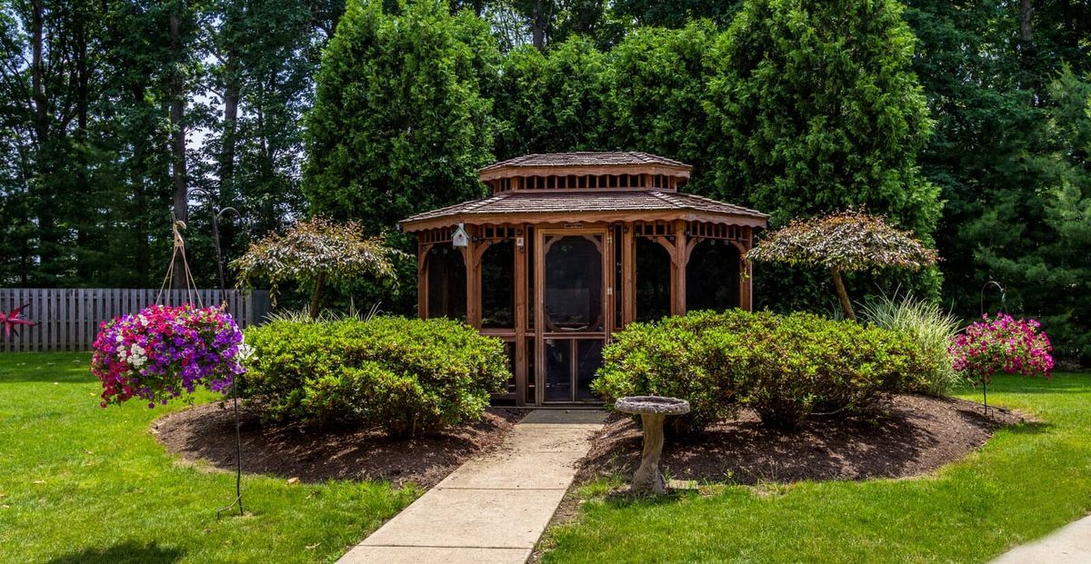 A picturesque gazebo surrounded by lush greenery and a well-maintained garden path.