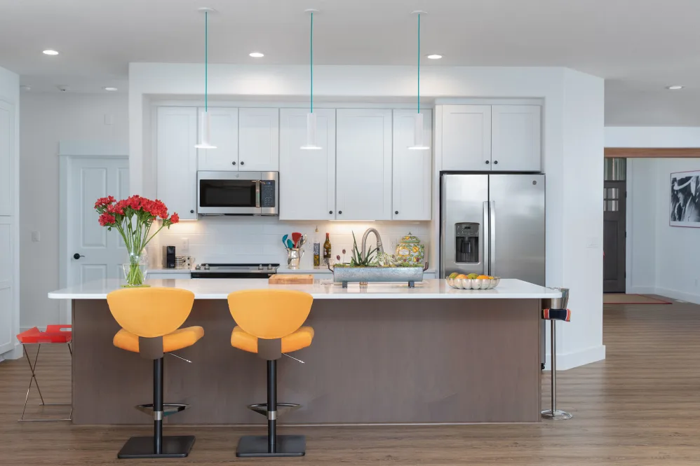 A modern kitchen with a central island and stylish stools.