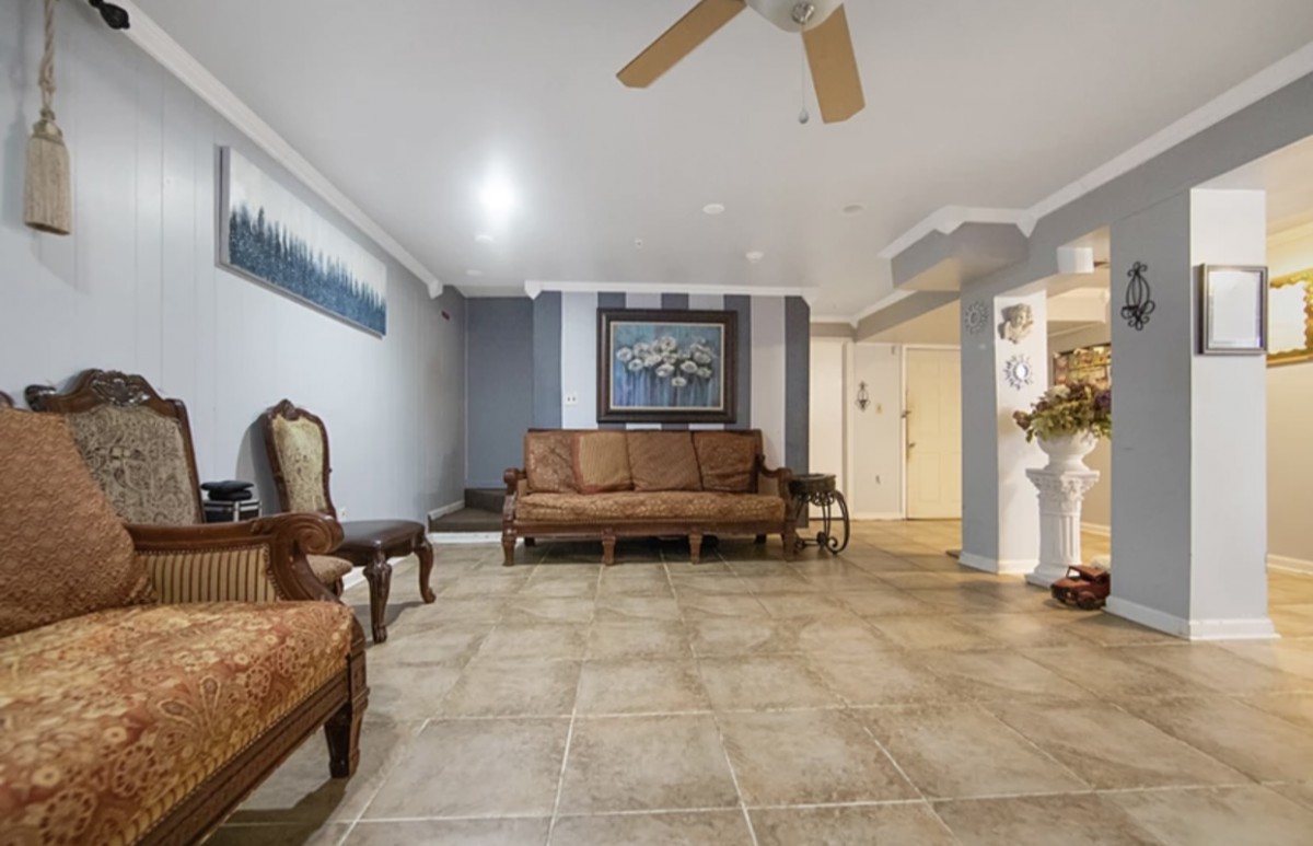 A spacious living room with a sofa, armchair, and tile flooring.