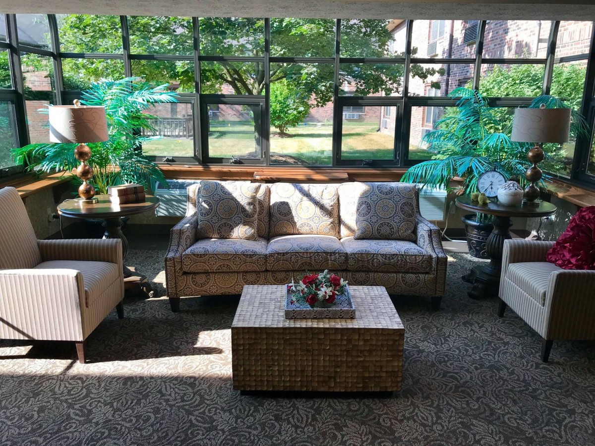 A cozy living room with wicker furniture and large windows letting in natural light.