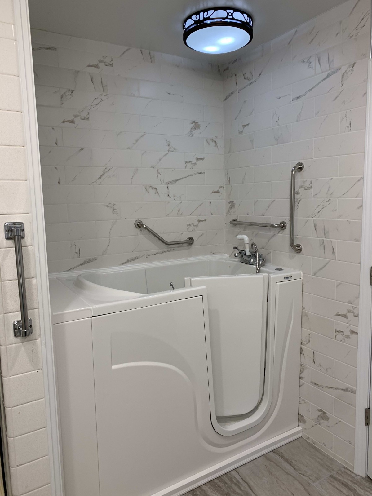A bathroom featuring a walk-in tub with accessibility grab bars.