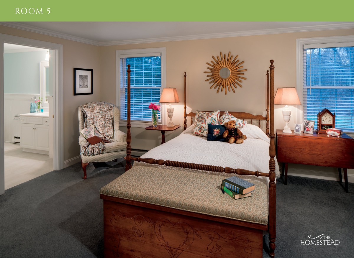 A cozy bedroom with a four-poster bed, comfortable chair, and elegant decor.