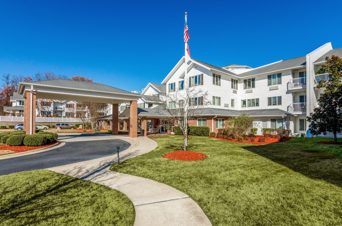 A scenic view of a senior living community with manicured lawns and an American flag.