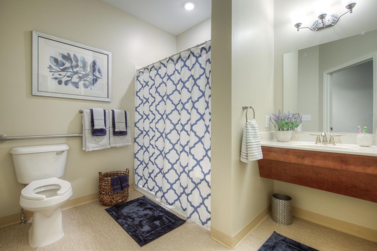 A neatly arranged bathroom featuring a geometric shower curtain, towels hanging on the rack, and decorative elements.