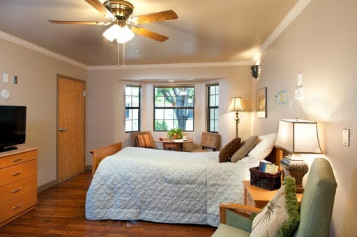 A cozy and inviting bedroom with natural light, featuring a ceiling fan and comfortable furnishings.