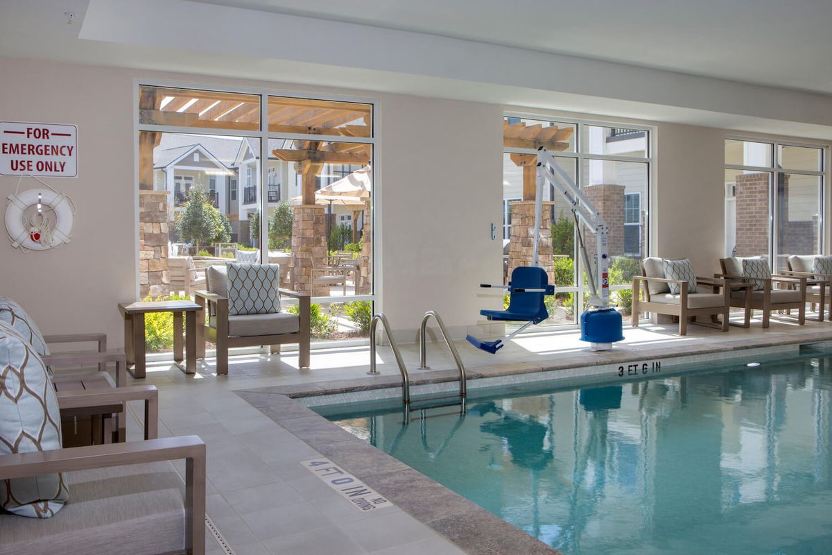 A modern indoor swimming pool with lounge seating and ample natural light streaming through large windows.