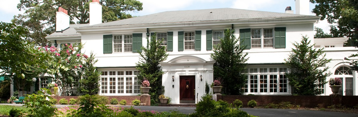 A colonial-style house with green shutters and a well-maintained front yard.