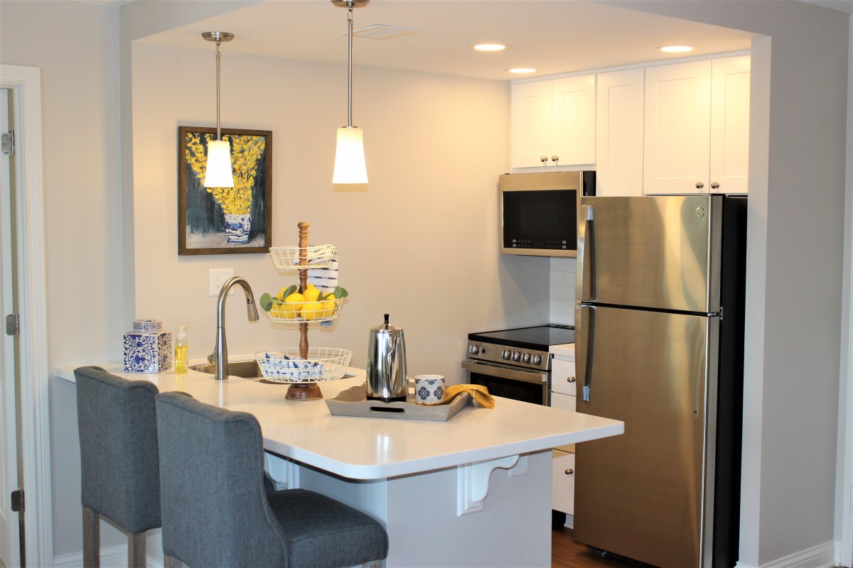 A modern kitchen with stainless steel appliances, a central island with seating, and stylish lighting.