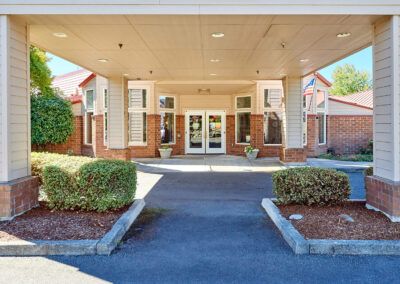 Entrance of a hotel with a covered driveway and surrounding landscaping.