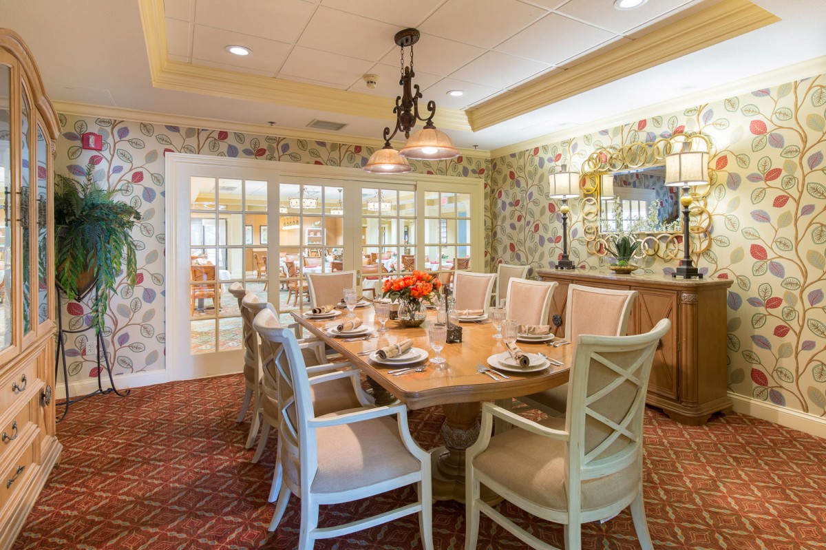 An elegant dining room with a well-decorated table and comfortable chairs, featuring a chandelier and a warm atmosphere.