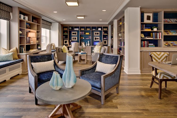 A cozy living room with armchairs and bookshelves, featuring decorative vases on a wooden table.